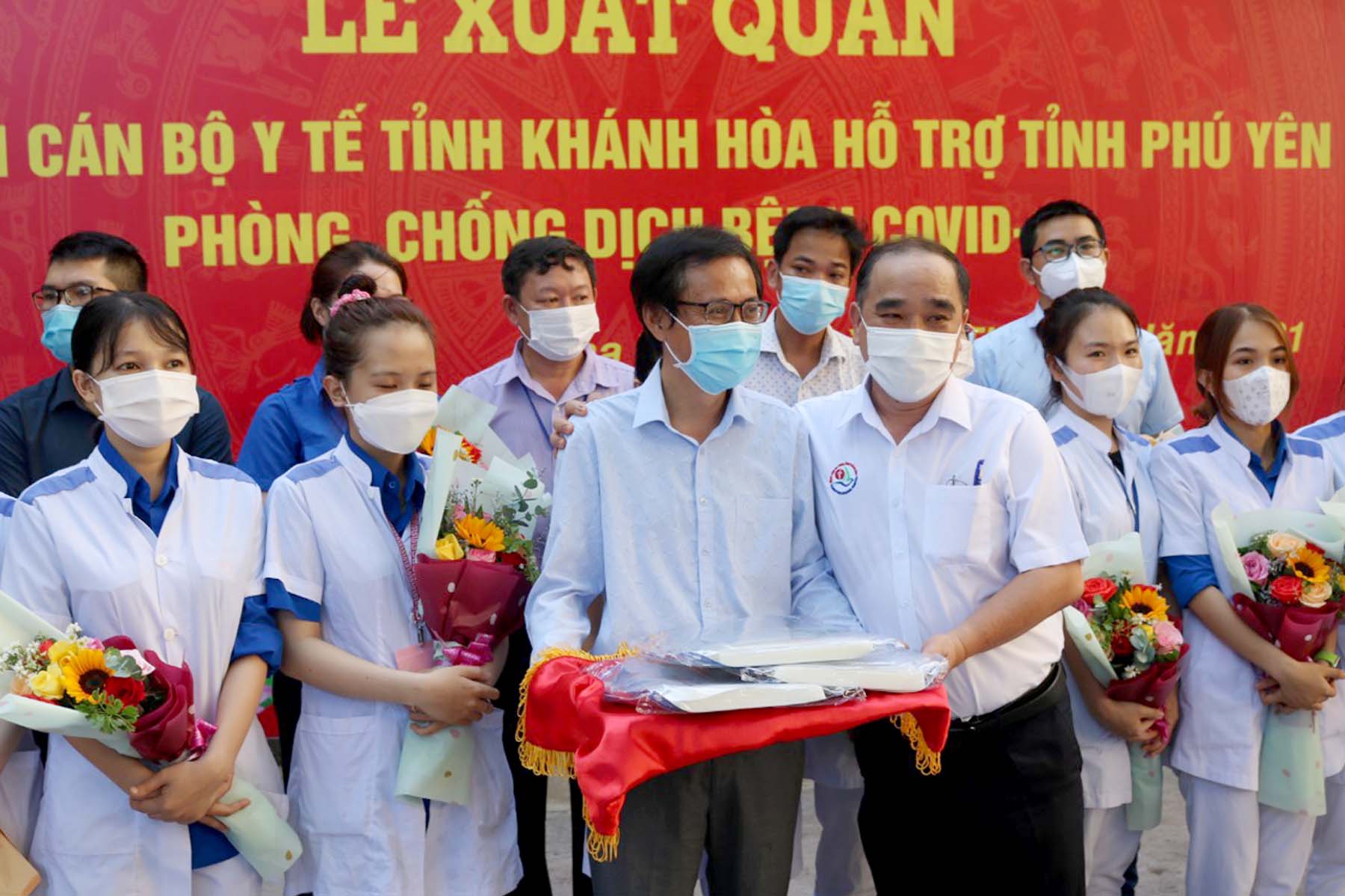 Bác sĩ Phan Hữu Chính (bên phải), Giám đốc Bệnh viện Đa khoa Khánh Hòa trao trang phục phòng hộ cho đoàn cán bộ y tế đi Phú Yên.